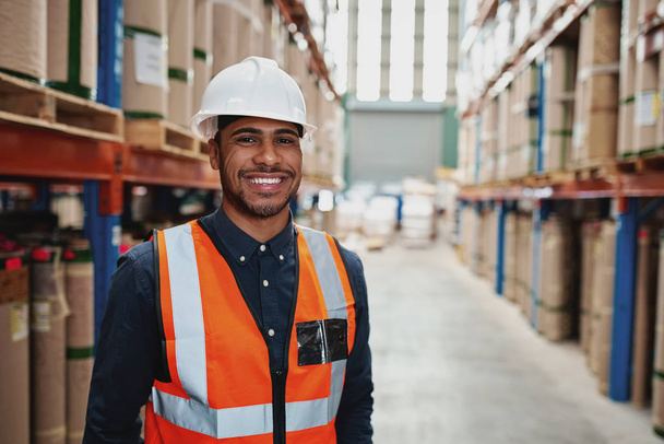 Happy male supervisor in warehouse standing in uniform with white hardhat smiling looking at camera - copy space on the right - Photo, image