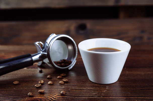 Filiżanka czarnej kawy i uchwyt filtra espresso. - Zdjęcie, obraz
