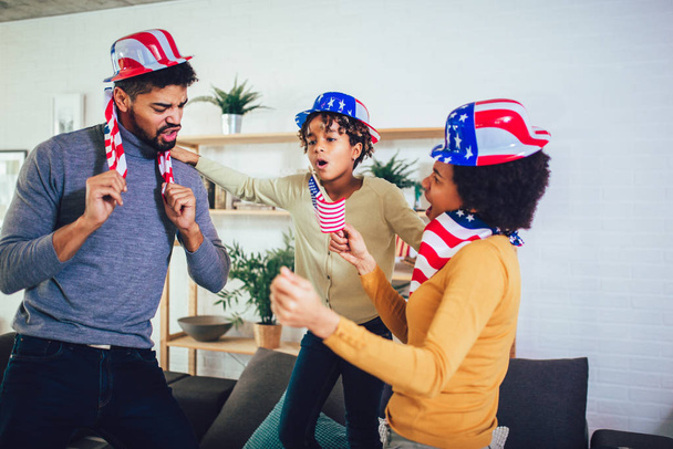 Family in living room on fourth of July with flags smiling - 写真・画像