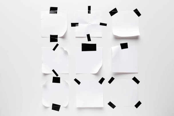 White ripped note paper stuck with black sticky tape on white background. - Foto, immagini