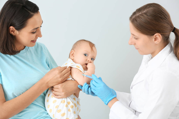Pediatra vacunando al pequeño bebé sobre fondo claro
 - Foto, imagen