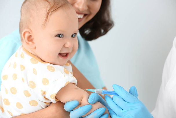 Pediatrician vaccinating little baby on light background - Photo, Image