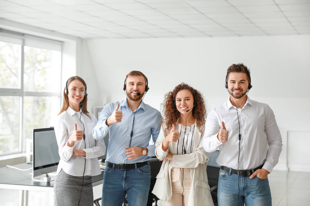 Portret van technische ondersteuningsagenten die duim omhoog steken in het kantoor - Foto, afbeelding