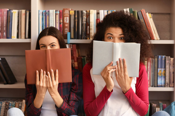 Female students with books preparing for exam in library - Фото, изображение