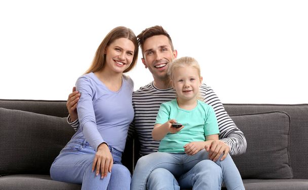 Boldog fiatal család néz TV-t, miközben ül a kanapén szemben fehér háttér - Fotó, kép