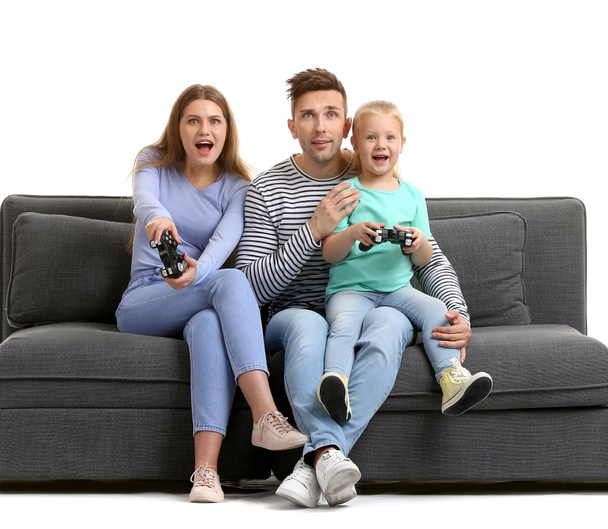 Familia joven jugando videojuegos mientras está sentado en el sofá contra el fondo blanco
 - Foto, imagen