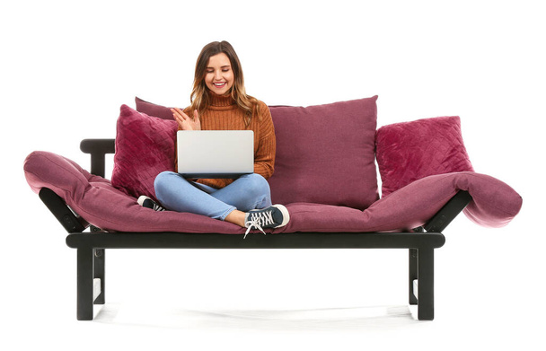 Молода жінка з ноутбуком сидить на дивані на білому тлі
 - Фото, зображення
