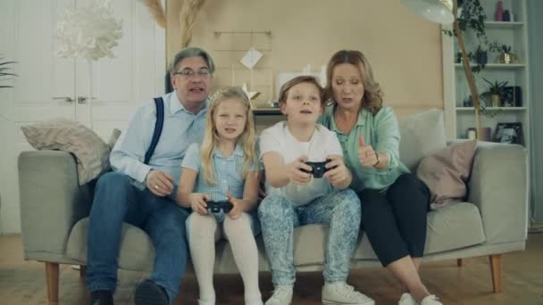 Kids are sitting with their grandparents and playing console - Video