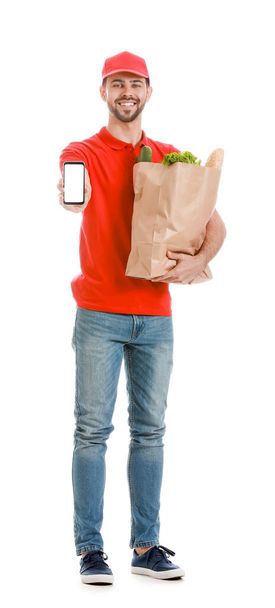 Beau travailleur du service de livraison de nourriture avec téléphone portable sur fond blanc
 - Photo, image