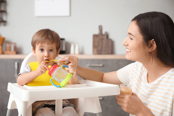 Mãe alimentando seu filhinho na cozinha
 - Foto, Imagem