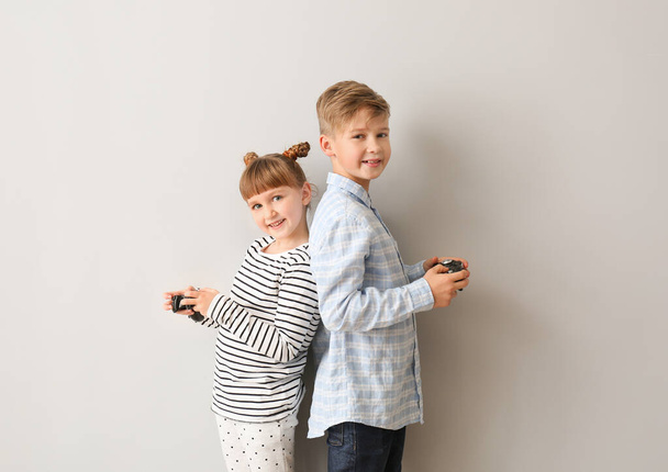 Little children playing video games on grey background - Foto, Imagem