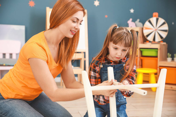 Mother and her little daughter assembling furniture at home - Foto, Bild