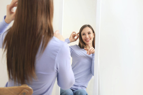 Krásná mladá žena hledá v zrcadle doma - Fotografie, Obrázek