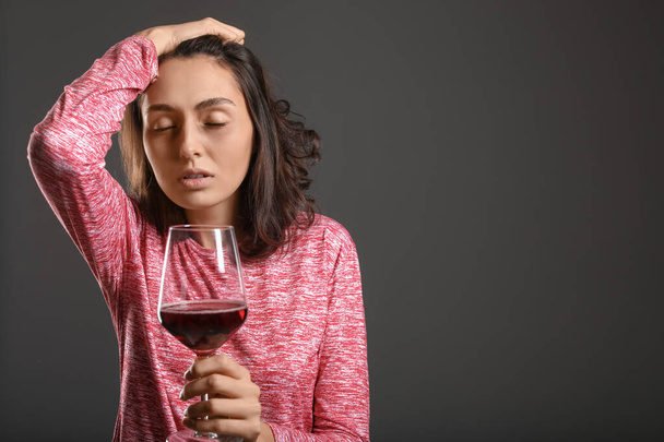 Young drunk woman on dark background. Concept of alcoholism - Photo, Image