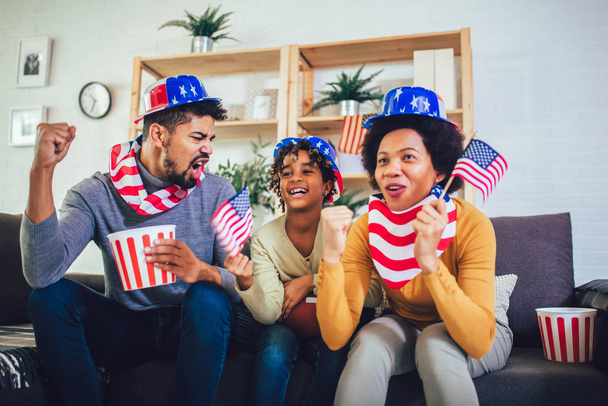 Happy African American family of three watching tv and cheering  - Photo, Image