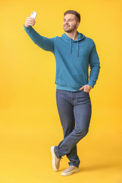 Young man taking selfie on color background - Foto, afbeelding