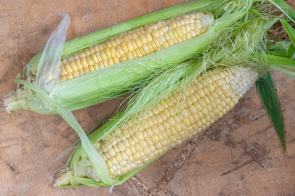 Top view on two organic corn ears lying on a wooden surface - Фото, зображення