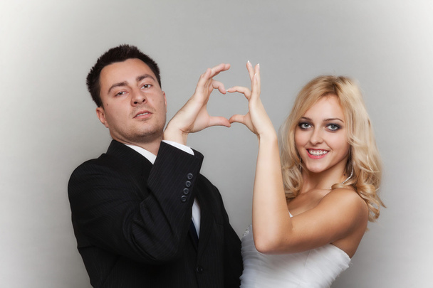 Portrait of happy bride and groom showing heart sign - Foto, Imagem