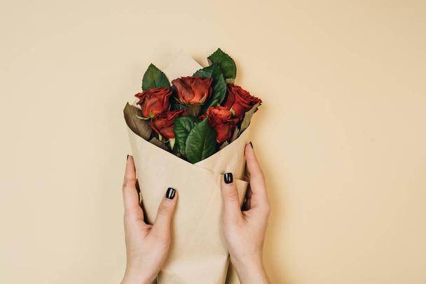 female hands holding beautiful bouquet with red roses, elegant floral decoration - Fotó, kép