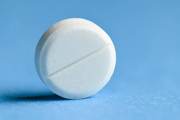 Una píldora blanca sobre fondo azul macro foto - concepto de medicina y tratamiento de medicamentos, atención médica
 - Foto, imagen