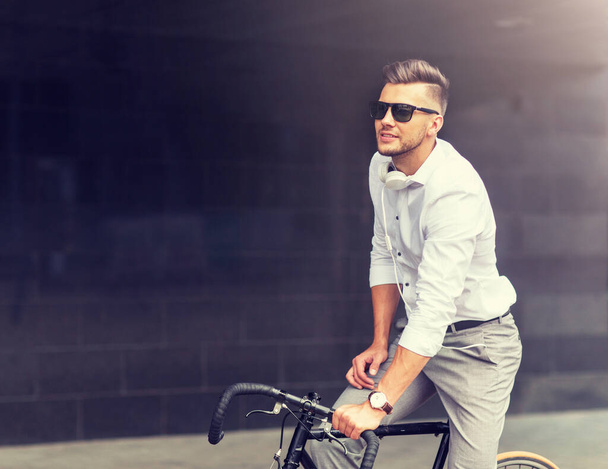 άνθρωπος με ποδήλατο και ακουστικά για τον δρόμο της πόλης - Φωτογραφία, εικόνα