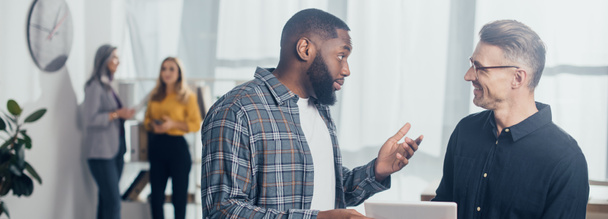 foto panorâmica do empresário afro-americano conversando com seu colega sorridente com tablet digital
  - Foto, Imagem