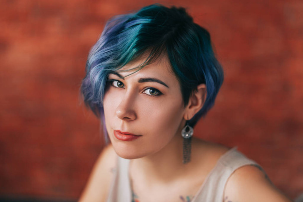 Όμορφη νεαρή γυναίκα με κομψά πράσινα και μοβ μαλλιά και τατουάζ στο σώμα της - Φωτογραφία, εικόνα