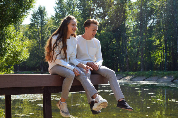 Ein junges Mädchen und ein junger Mann auf einem Holzsteg am Wasser - Foto, Bild
