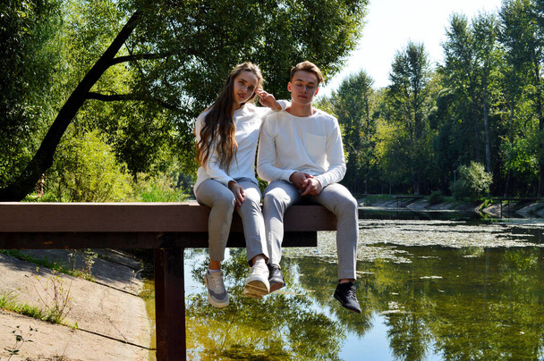 Młoda dziewczyna i młody mężczyzna na drewnianym molo w pobliżu wody - Zdjęcie, obraz