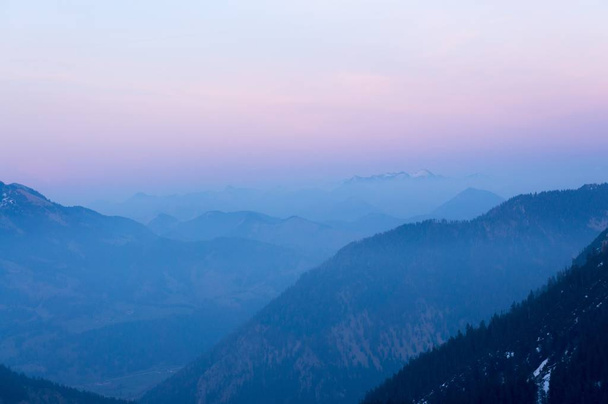 A breathtaking aerial shot of mountains during daytime under a pastel sky - Foto, imagen