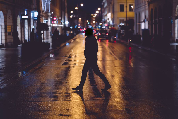 MUNICH, GERMANY - Feb 01, 2020: People crossing the street during a wet rainy night in Munich. Neon lights illuminating the scene. City traffic in the background. - Φωτογραφία, εικόνα