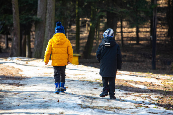 dva kluci v zimním oblečení procházky kolem zasněženého parku - Fotografie, Obrázek