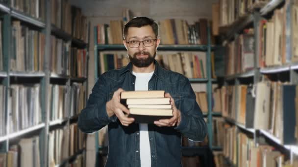 A bearded man in glasses suggests reading several books - Video
