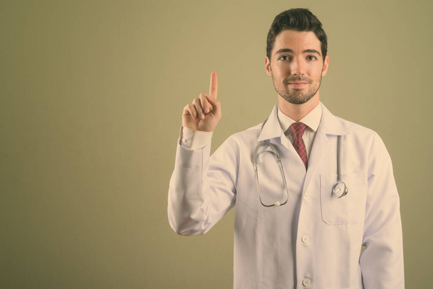 Jonge knappe man arts tegen gekleurde achtergrond - Foto, afbeelding