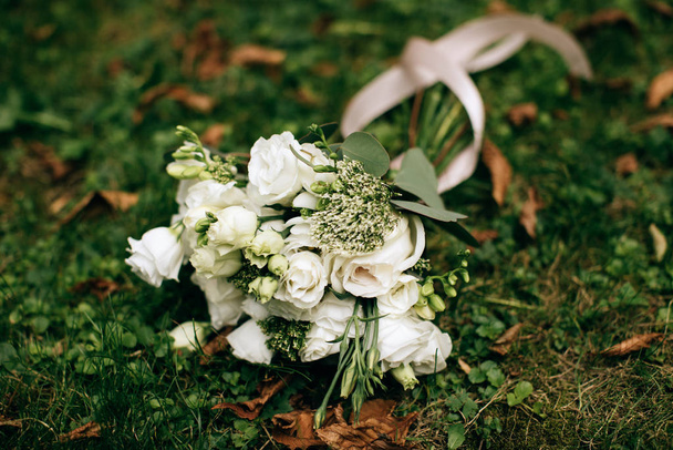 Μπουκέτο με λευκά τριαντάφυλλα στο πράσινο γρασίδι. Διακόσμηση και αξεσουάρ γάμου - Φωτογραφία, εικόνα