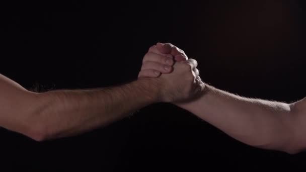 Caucasian males express sport handshake on black background, close up isolated - Video