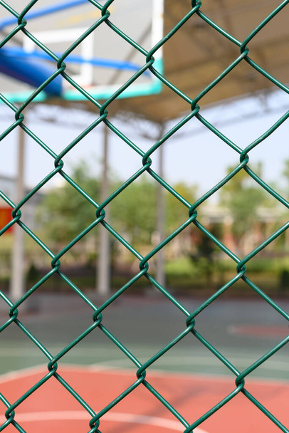 outdoor basketball court behind a metal fence vertical composition - Zdjęcie, obraz