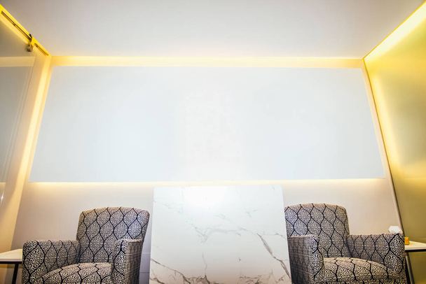 Sala de espera com duas poltronas e um grande bloco de mármore e painel branco em branco na parede de fundo. - Foto, Imagem