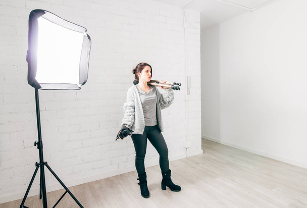 Ammattimainen naisvalokuvaaja, jolla on kamera-, kolmijalka ja valaistuslaitteet studiossa
 - Valokuva, kuva