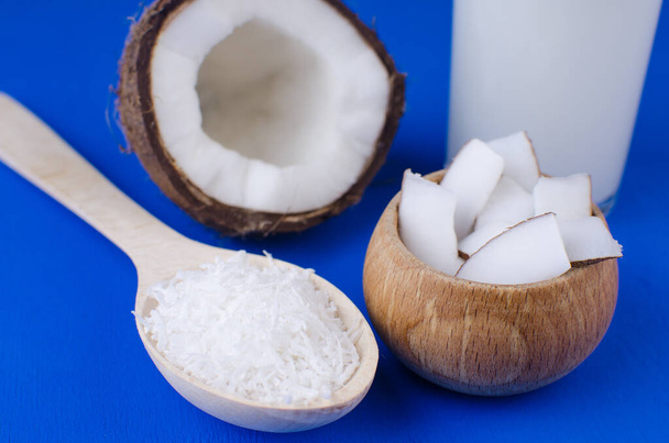 天然ココナッツミルク、ココナッツシェービング、青の背景にココナッツチップ。健康食品の概念. - 写真・画像