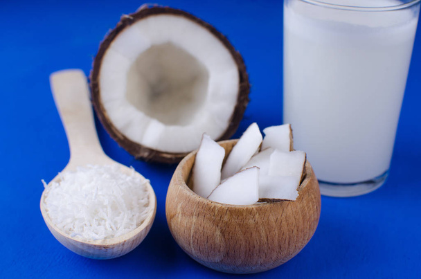 天然ココナッツミルク、ココナッツシェービング、青の背景にココナッツチップ。健康食品の概念. - 写真・画像