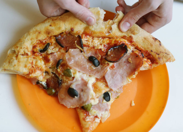 rebanada de pizza con zumbido, salchicha, pepino, cebolla aceituna y queso
 - Foto, Imagen