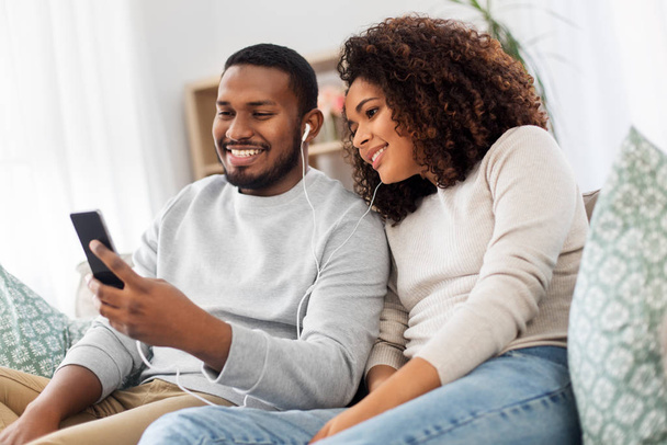 happy couple with smartphone and earphones at home - Photo, image