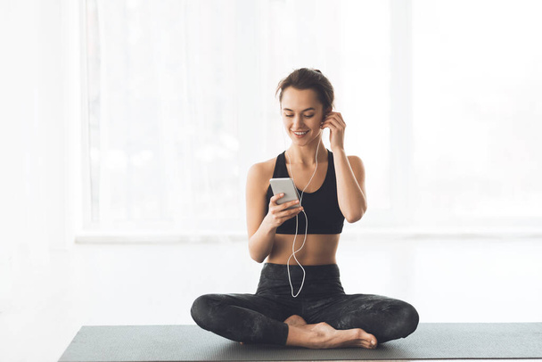 Woman Relaxing With Smartphone At Yoga Class - Фото, изображение
