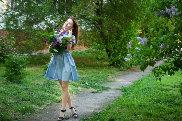 Beautiful woman in a blue summer dress with lilac flowers in a b - Zdjęcie, obraz