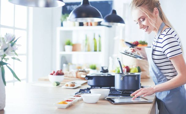Young woman using a tablet computer to cook in her kitchen - Фото, зображення
