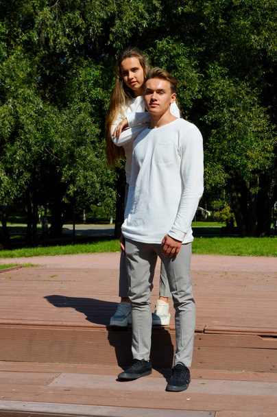 Egy fiatal lány és egy fiatalember egy fából készült mólón a víz mellett. - Fotó, kép
