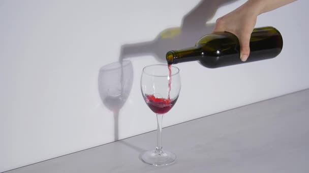 Conceptual shot, pouring red wine into a glass on a gray background - Video, Çekim