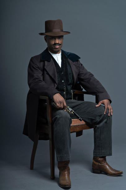 Homem cowboy ocidental retro afro-americano com bigode. Sentado em
 - Foto, Imagem