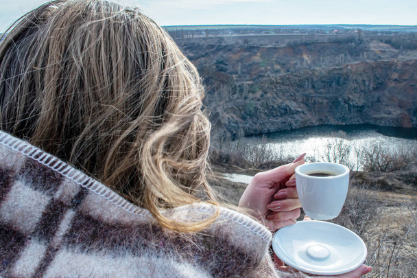 A woman in a plaid with a cup of coffee looks at a canyon - Photo, Image